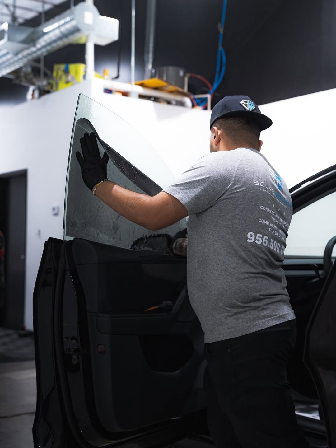 Black Diamond RGV installer prepping tint film on a door glass panel in McAllen